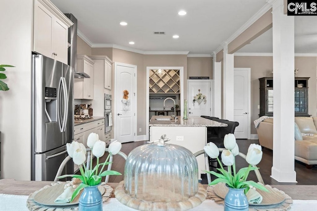 kitchen with dark wood-type flooring, an island with sink, stainless steel fridge with ice dispenser, white cabinets, and light stone counters