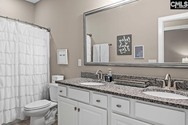 bathroom with toilet, vanity, and tile patterned flooring