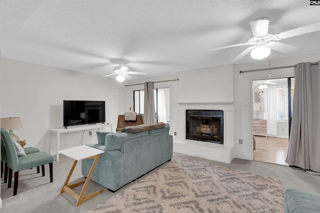 living room featuring carpet, ceiling fan, and a textured ceiling