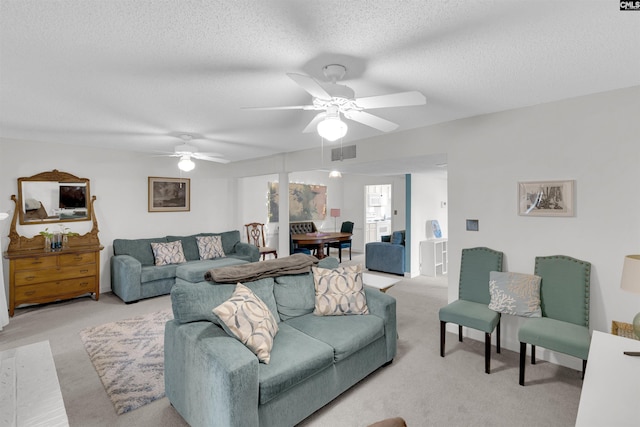 living room with ceiling fan, a textured ceiling, and light carpet