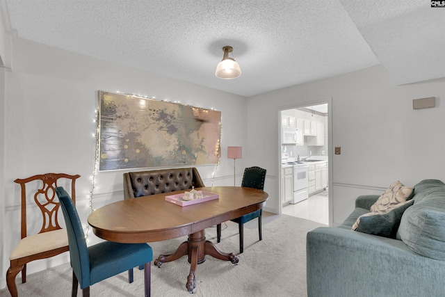 dining area with a textured ceiling and light carpet