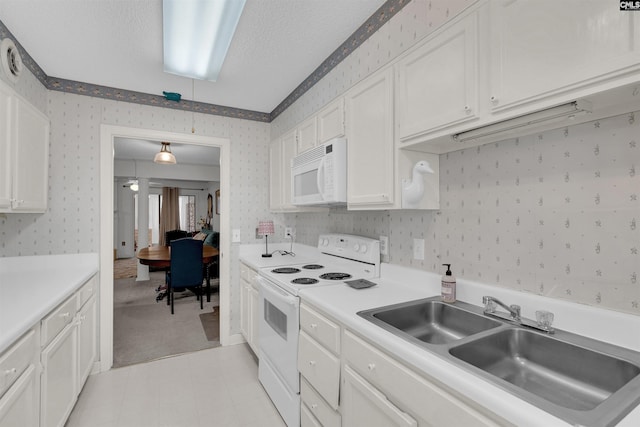 kitchen with a textured ceiling, white appliances, white cabinetry, and sink