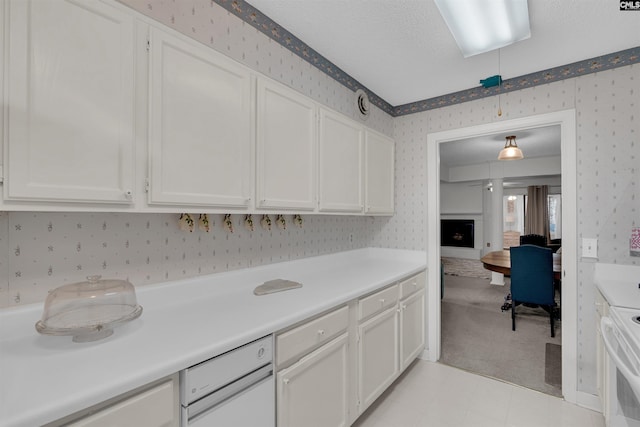 kitchen featuring range, a textured ceiling, decorative light fixtures, and white cabinetry