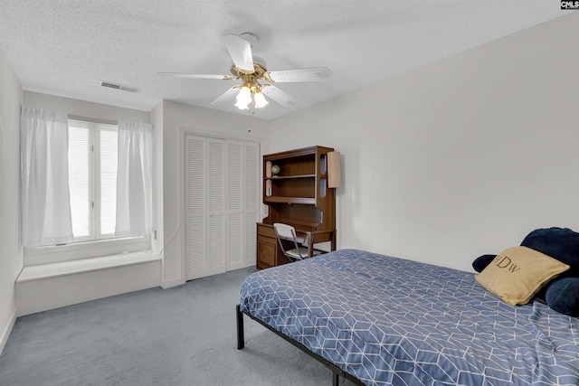 bedroom featuring a textured ceiling, carpet floors, a closet, and ceiling fan