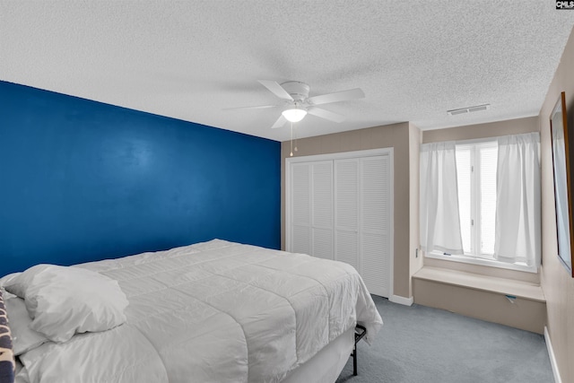 bedroom with ceiling fan, a closet, light carpet, and a textured ceiling