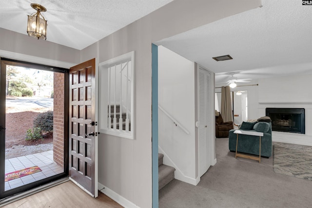 carpeted entryway with ceiling fan with notable chandelier and a textured ceiling