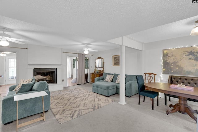 carpeted living room featuring ceiling fan, a textured ceiling, and decorative columns