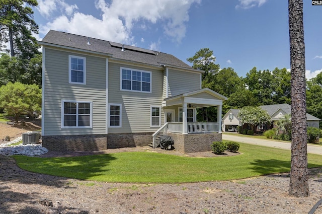 back of house with a lawn, central AC unit, a porch, and solar panels