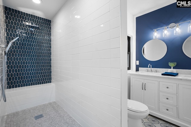 bathroom featuring toilet, a tile shower, vanity, and tile patterned floors