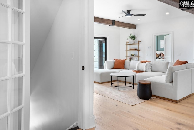 living room with ceiling fan, beam ceiling, and light hardwood / wood-style flooring