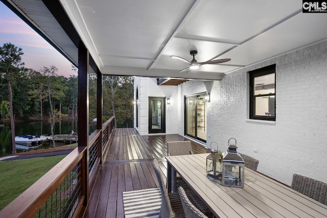 deck at dusk featuring a yard and ceiling fan