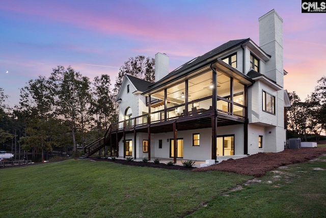 back house at dusk featuring a yard, central AC unit, a deck, and ceiling fan