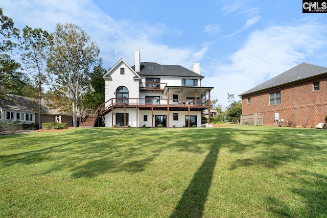 rear view of property featuring a yard, a wooden deck, and a balcony