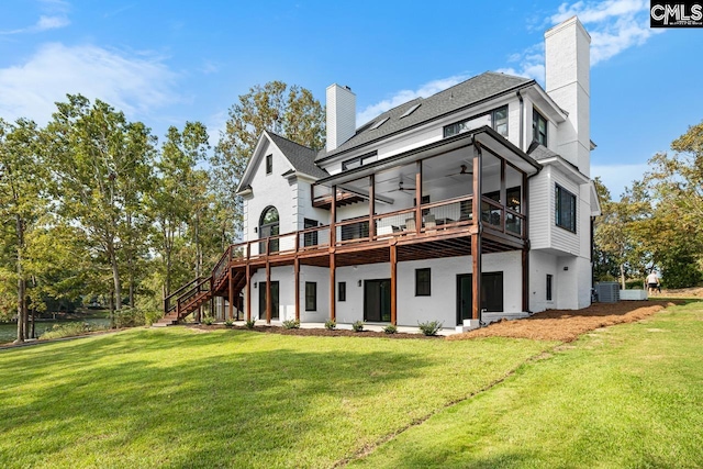 back of property with a lawn, ceiling fan, and a wooden deck