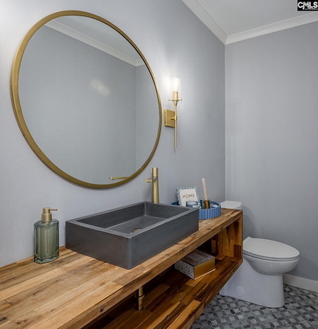 bathroom with toilet, crown molding, and sink