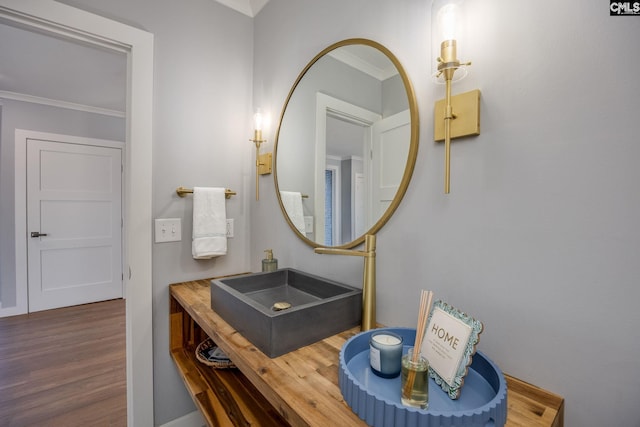 bathroom featuring wood-type flooring, ornamental molding, and sink