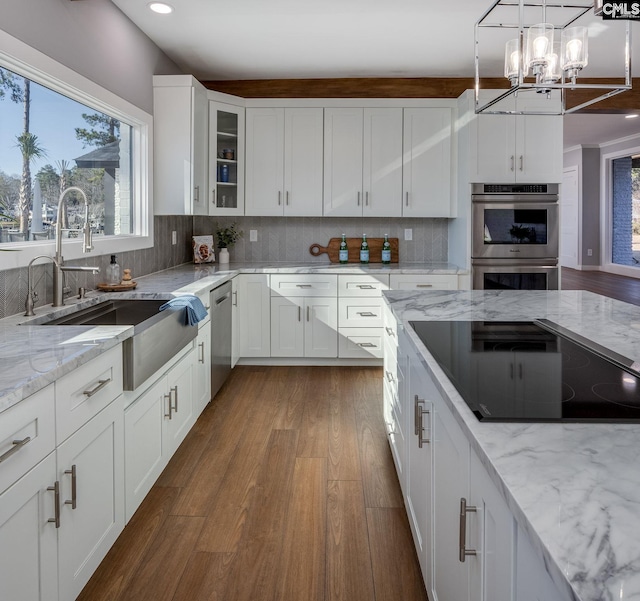 kitchen with sink, decorative backsplash, decorative light fixtures, white cabinetry, and stainless steel appliances