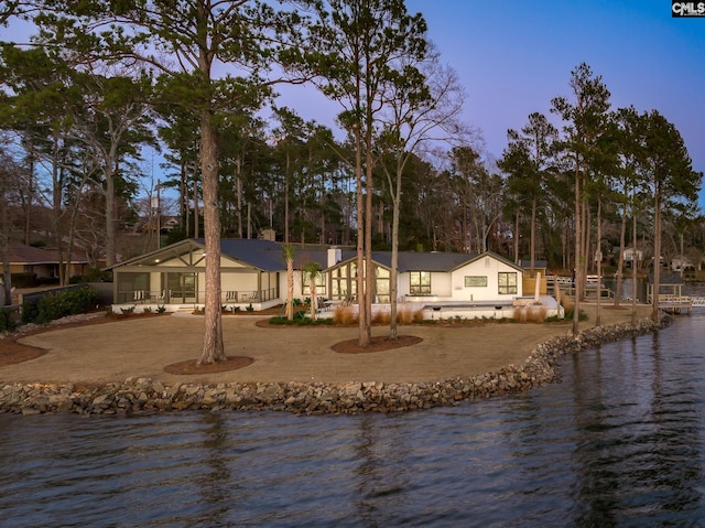 back house at dusk with a water view and a patio