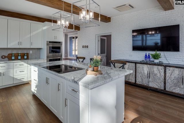 kitchen with white cabinets, beam ceiling, black electric cooktop, and a center island with sink