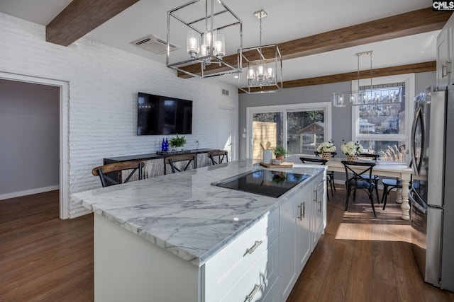 kitchen with white cabinets, a center island, beam ceiling, and pendant lighting