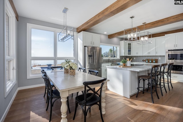 dining area featuring beam ceiling, dark hardwood / wood-style floors, and an inviting chandelier