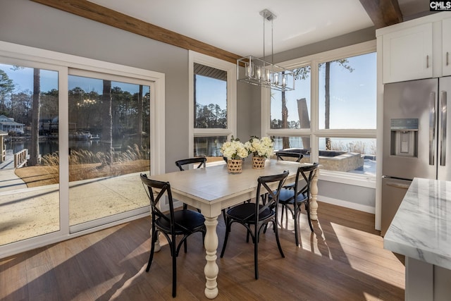 dining space featuring hardwood / wood-style floors, a water view, and a notable chandelier