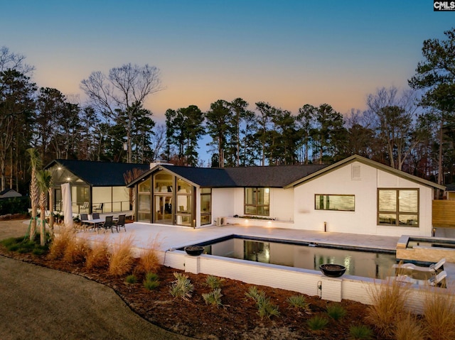 back house at dusk with a patio area