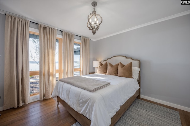 bedroom with hardwood / wood-style floors, crown molding, and an inviting chandelier