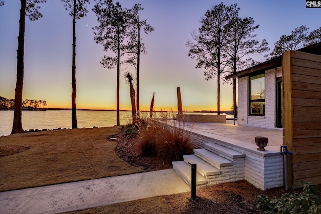 deck at dusk featuring a water view