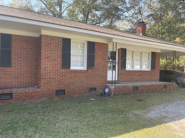 single story home with a front yard, a carport, and covered porch