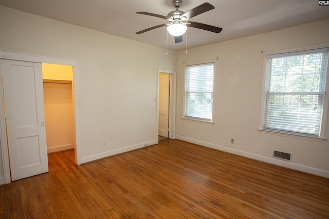 unfurnished bedroom with hardwood / wood-style flooring, ceiling fan, a spacious closet, and a closet