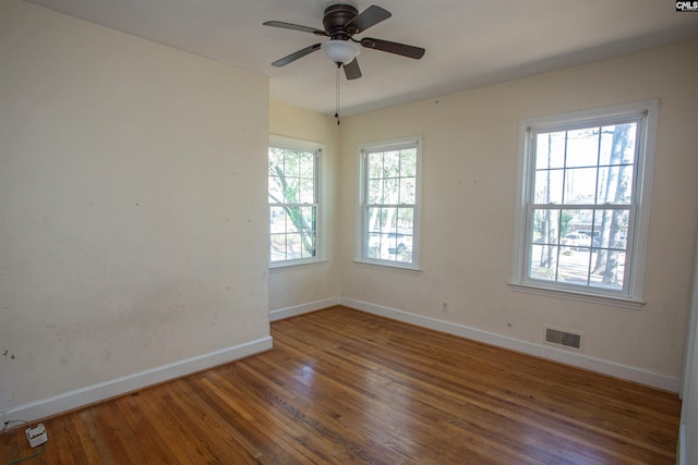 spare room featuring a wealth of natural light, ceiling fan, and dark wood-type flooring