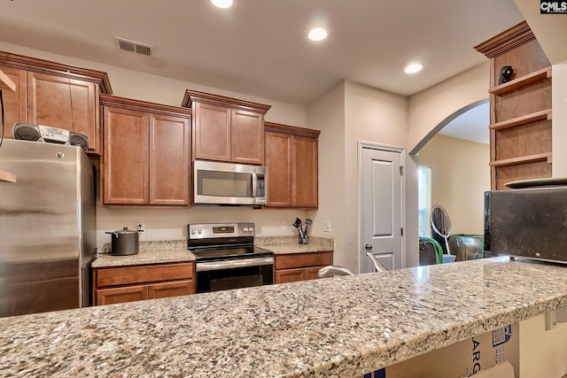 kitchen featuring kitchen peninsula, stainless steel appliances, and light stone counters