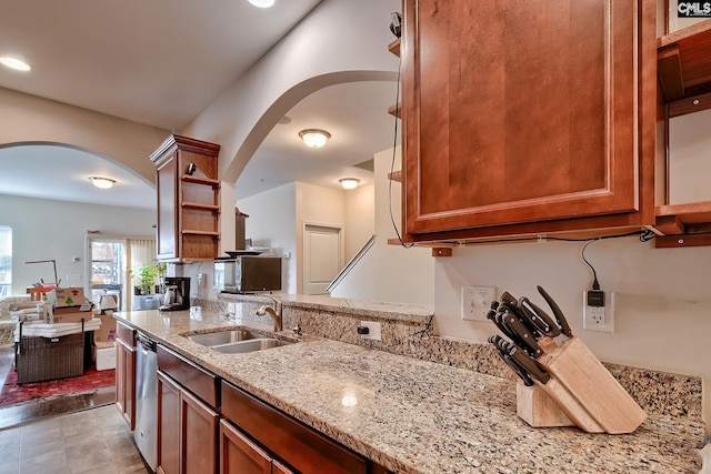 kitchen featuring stainless steel dishwasher, light stone counters, and sink