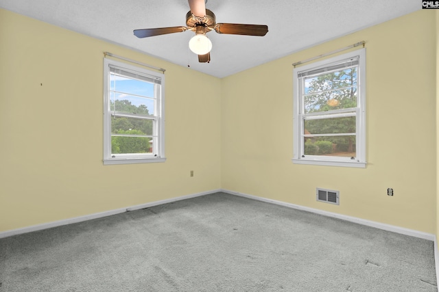 spare room featuring ceiling fan, light carpet, and a wealth of natural light