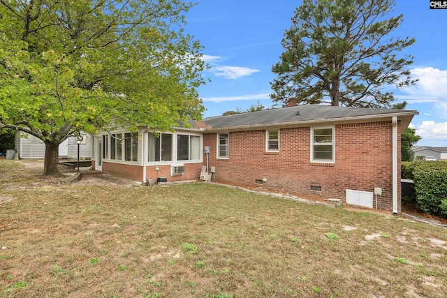 rear view of property featuring a lawn and a sunroom