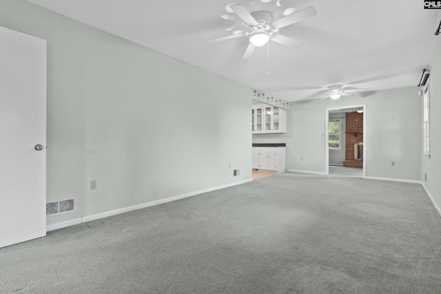 unfurnished living room featuring ceiling fan, carpet floors, and a textured ceiling