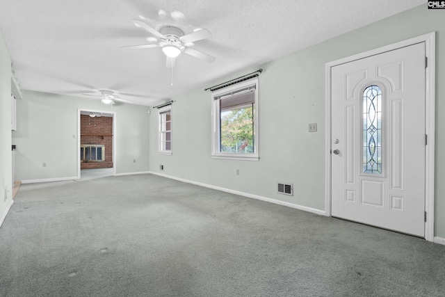 carpeted foyer featuring a fireplace, a textured ceiling, plenty of natural light, and ceiling fan