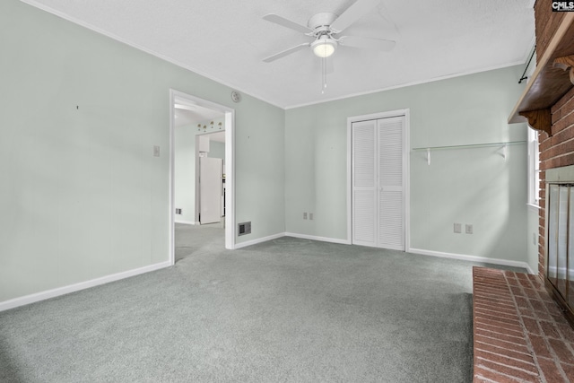 unfurnished living room with carpet flooring, ceiling fan, a fireplace, and crown molding