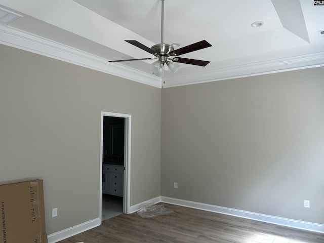 unfurnished bedroom with dark hardwood / wood-style flooring, ensuite bathroom, a raised ceiling, ceiling fan, and crown molding