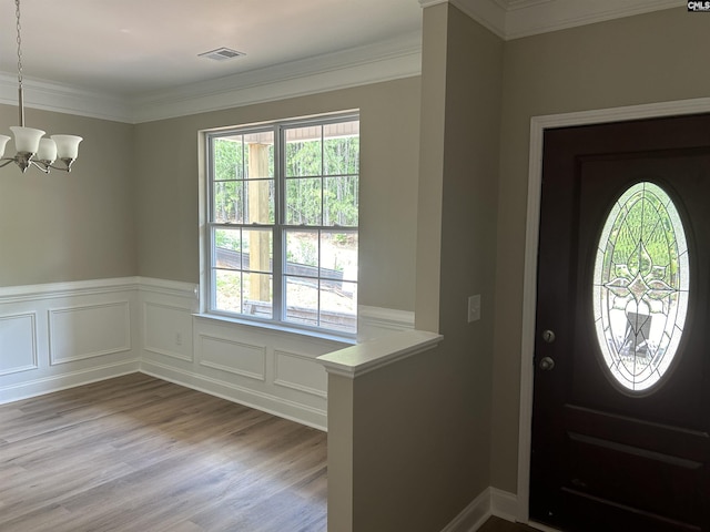 foyer featuring a chandelier, light hardwood / wood-style floors, and ornamental molding