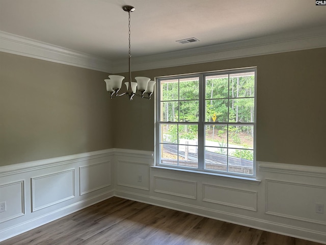 empty room featuring a notable chandelier, wood-type flooring, crown molding, and a wealth of natural light