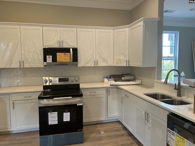 kitchen with tasteful backsplash, white cabinetry, sink, and stainless steel appliances