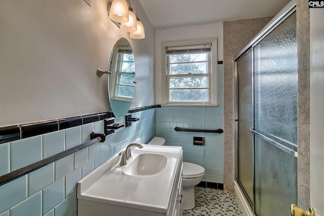 bathroom with vanity, toilet, a shower with door, and tile walls