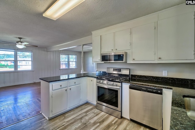 kitchen featuring white cabinetry, ceiling fan, kitchen peninsula, a textured ceiling, and appliances with stainless steel finishes