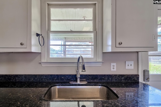 kitchen featuring sink, white cabinets, and dark stone counters