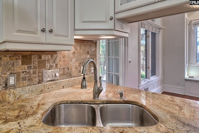 kitchen with white cabinets, light stone counters, sink, and tasteful backsplash