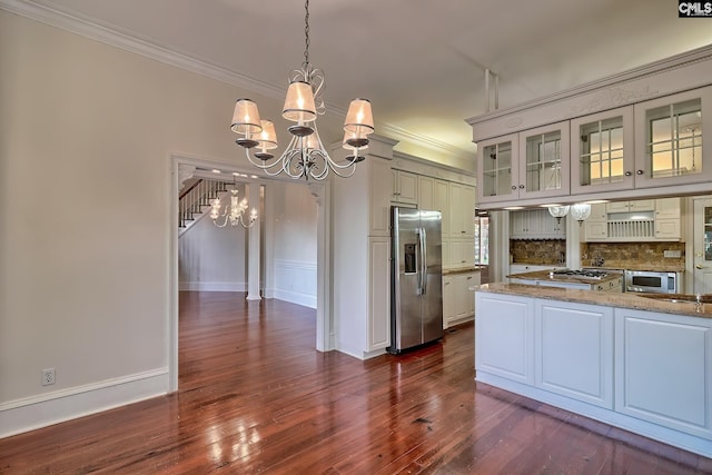 kitchen featuring stainless steel appliances, light stone counters, pendant lighting, decorative backsplash, and white cabinets