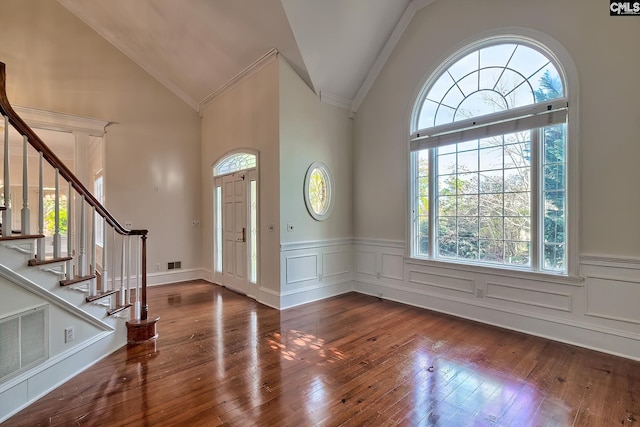 entrance foyer with dark wood-type flooring, high vaulted ceiling, plenty of natural light, and ornamental molding