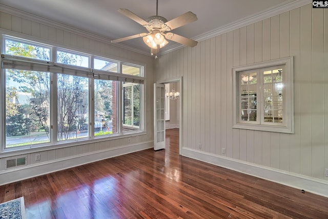 empty room featuring dark hardwood / wood-style flooring, ceiling fan with notable chandelier, and ornamental molding